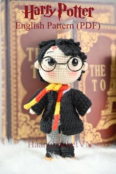 a crocheted harry potter doll standing in front of a book