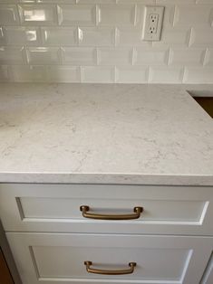 a white kitchen counter top with gold handles and knobs on the drawer pulls in front of it