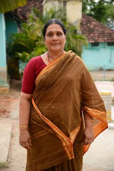 a woman in a brown sari is standing outside