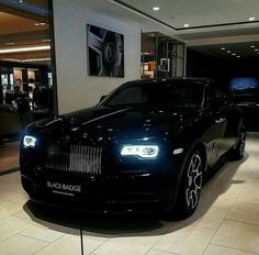 a black rolls royce parked in a showroom