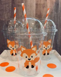 four cups with orange and white paper straws in the shape of foxes on them