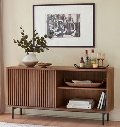 a wooden cabinet sitting next to a window filled with books and drinks on top of a rug