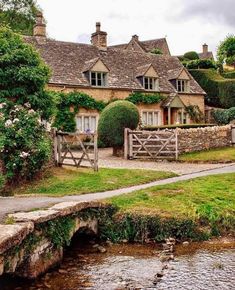 a stone house sitting next to a small stream in front of it's entrance