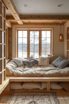 a living room filled with lots of furniture next to a large window covered in pillows