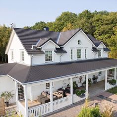 an aerial view of a large white house with black roofing and covered patio area