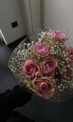 a bouquet of pink roses and baby's breath in a clear vase on a table