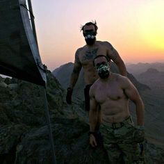 two shirtless men standing on top of a mountain