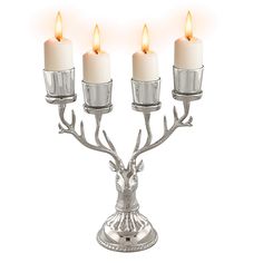 three candles are lit on a silver candelabra with antlers and branches