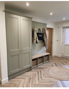 an empty room with wooden flooring and grey cupboards on either side of the door