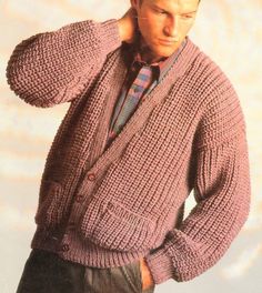 a man wearing a sweater and tie standing in front of a white wall with his hands on his head