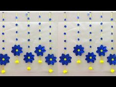 blue and yellow paper flowers hanging from strings on a white wall with balls in the middle