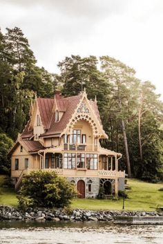 a large house sitting on top of a lush green hillside next to a body of water