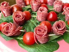 there is a pink cake decorated with ham and cherry tomatoes on the top it has green leaves