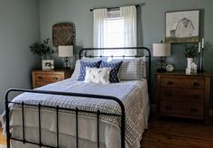 a bed sitting in a bedroom next to a window with curtains on the windowsill