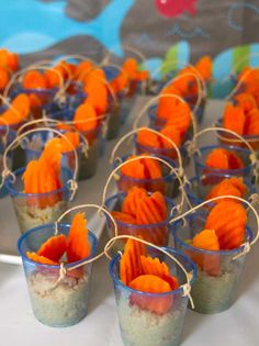 small cups filled with food sitting on top of a white table covered in orange and blue decorations