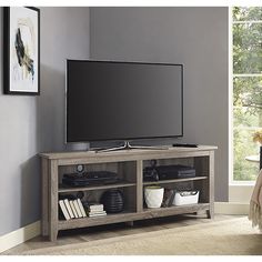 a flat screen tv sitting on top of a wooden entertainment center next to a window