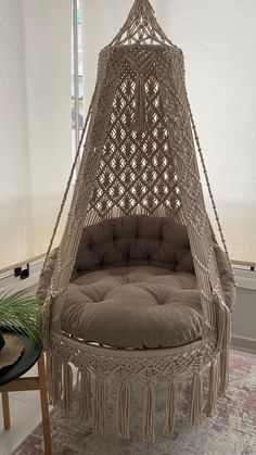 a hammock hanging in the middle of a room with a chair underneath it