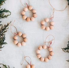 small wooden beads are hanging from twine strings on a white surface surrounded by evergreen branches