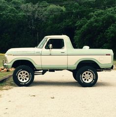 a light green and white truck parked in front of some trees