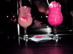 two drinks sitting on top of a table next to each other in front of a bar