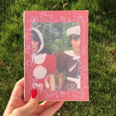 a hand holding up a polaroid with two girls dressed as santa and mrs claus