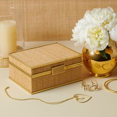 a vase with white flowers sitting next to a gold box and some other items on a table