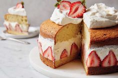 a cake with strawberries and whipped cream on top sits on a plate next to another piece of cake