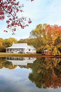 a white house sitting on top of a lake surrounded by trees