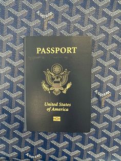 a black passport sitting on top of a blue and white patterned table cloth with the united states of america written on it