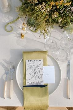 the place setting is set with silverware and napkins, along with an elegant floral centerpiece