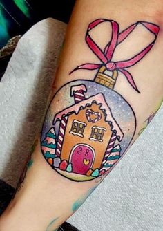 a woman's leg with a tattoo on it that has a gingerbread house and a pink ribbon