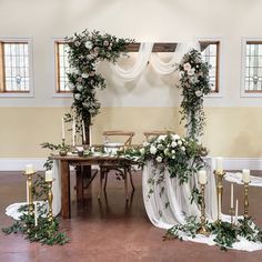 a table with white flowers and greenery is set up for an outdoor wedding ceremony