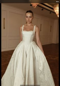 a woman in a white dress standing on a wooden floor