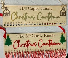 two wooden christmas signs hanging on a wall with candy canes in front of them