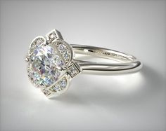 a white gold ring with an oval cut diamond surrounded by smaller round diamonds on the band