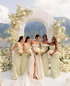 a group of women standing next to each other in front of a flower covered arch