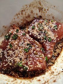 two pieces of meat covered in sesame seeds and garnished with seasoning sprinkles