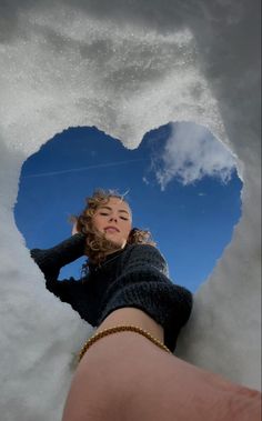 a heart shaped hole in the snow with a woman's hand next to it