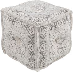 a white and black square ottoman with an intricate design on the top, in front of a