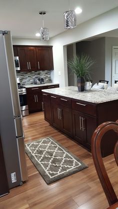 a large kitchen with wooden floors and dark wood cabinets, white counter tops, and stainless steel appliances