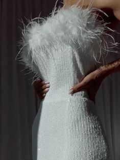 a woman in a white dress with feathers on it