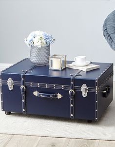 a blue suitcase sitting on top of a white rug next to a table with flowers