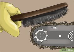 a hand with a yellow glove holding a brush over a metal chain link saw blade