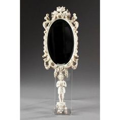 an ornate white and black mirror is on display in front of a gray background,