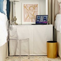 a laptop computer sitting on top of a white table next to a chair and lamp