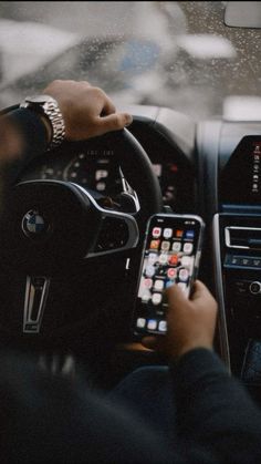 a person holding a cell phone in their hand while sitting in the driver's seat of a car