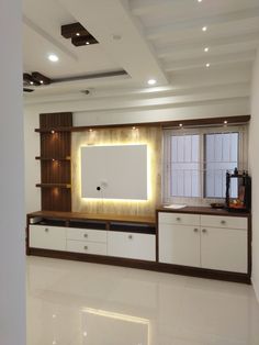 an empty living room with white cabinets and lights on the wall, along with a large flat screen tv