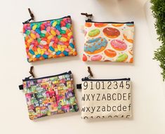 four zippered pouches with different designs and letters on them, all decorated in various colors