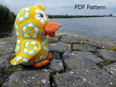 a crocheted stuffed animal sitting on top of a rock next to the water