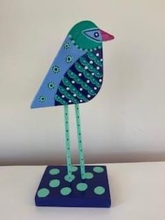 a blue and green bird sitting on top of a polka dot covered table cloth next to a white wall